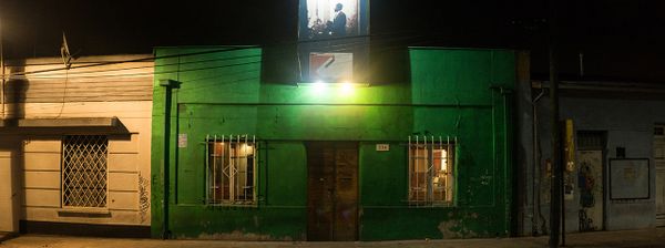 The front Entrance to Thelonious jazz club, with green walls and a lit portrait of Thelonious Monk above the front door.